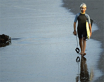 Surfer walking on wet sand